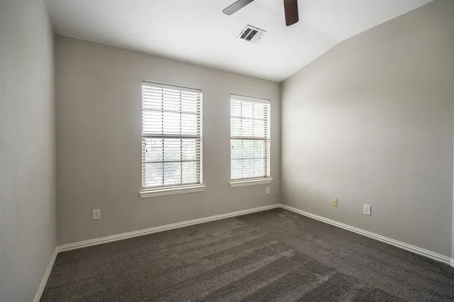 an empty room with wooden floor ceiling fan and windows