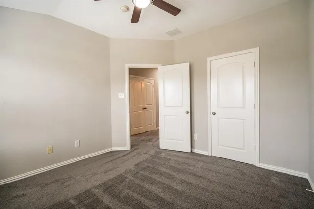 an empty room with closet and a chandelier fan