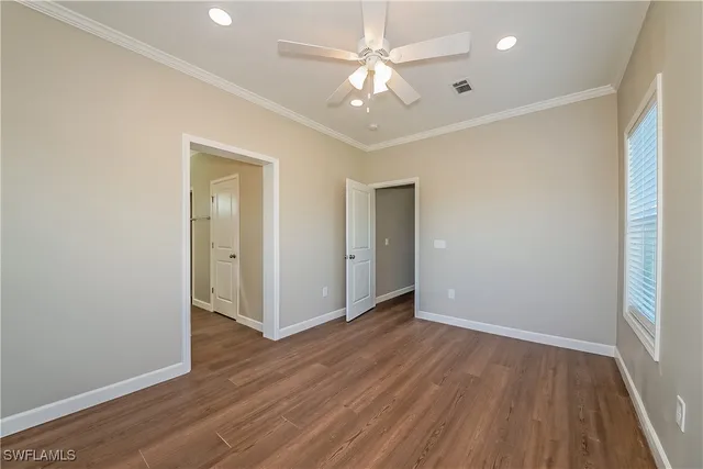 an empty room with wooden floor and a ceiling fan