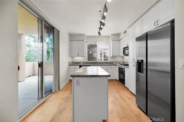 a kitchen with stainless steel appliances granite countertop a refrigerator a sink and a stove