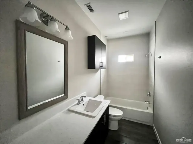 a bathroom with a granite countertop bathtub shower sink vanity and toilet