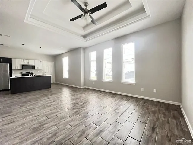 a view of an empty room with kitchen stove and wooden floor