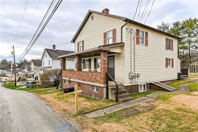 a view of a white house with a yard and lawn chairs next to a yard