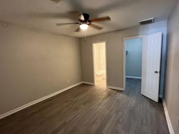 an empty room with wooden floor and fan