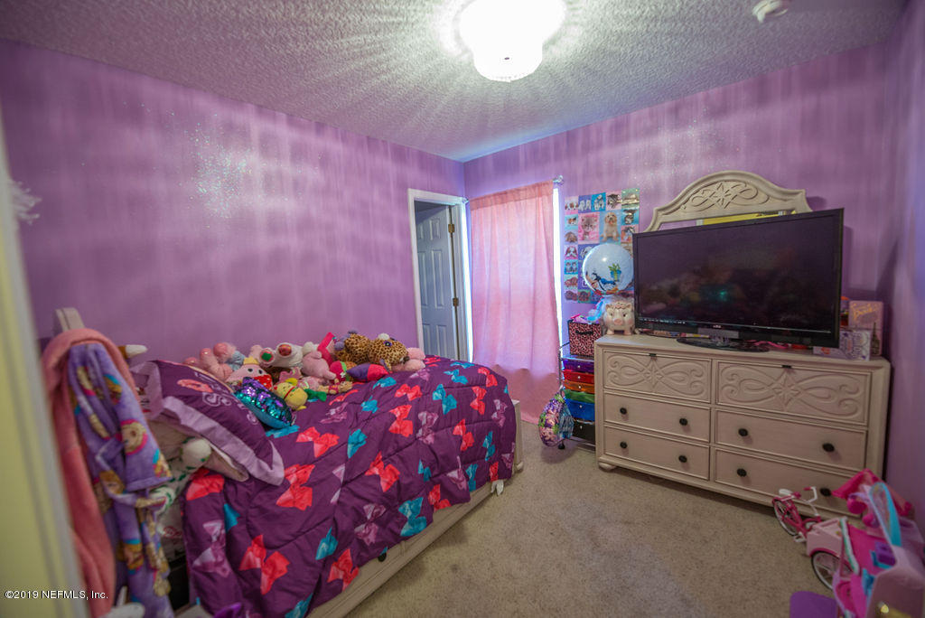 9171 Raptor Drive Jacksonville, FL 32221 - Photo 7 of 13 a bedroom with furniture and a flat screen tv