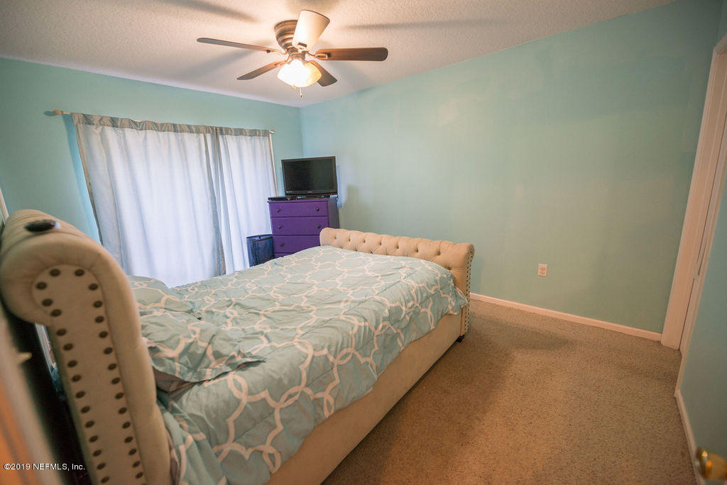 9171 Raptor Drive Jacksonville, FL 32221 - Photo 9 of 13 a bedroom with a bed and a chandelier
