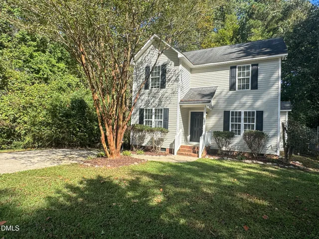 a front view of a house with a yard and trees