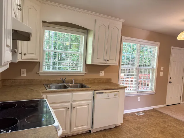 a kitchen with white cabinets sink and window