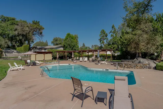 a swimming pool with outdoor seating and barbeque oven