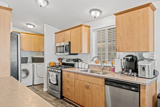 a kitchen with stainless steel appliances a sink cabinets and a window