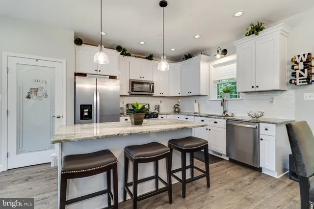 a kitchen with stainless steel appliances granite countertop a sink a stove a refrigerator cabinets and chairs