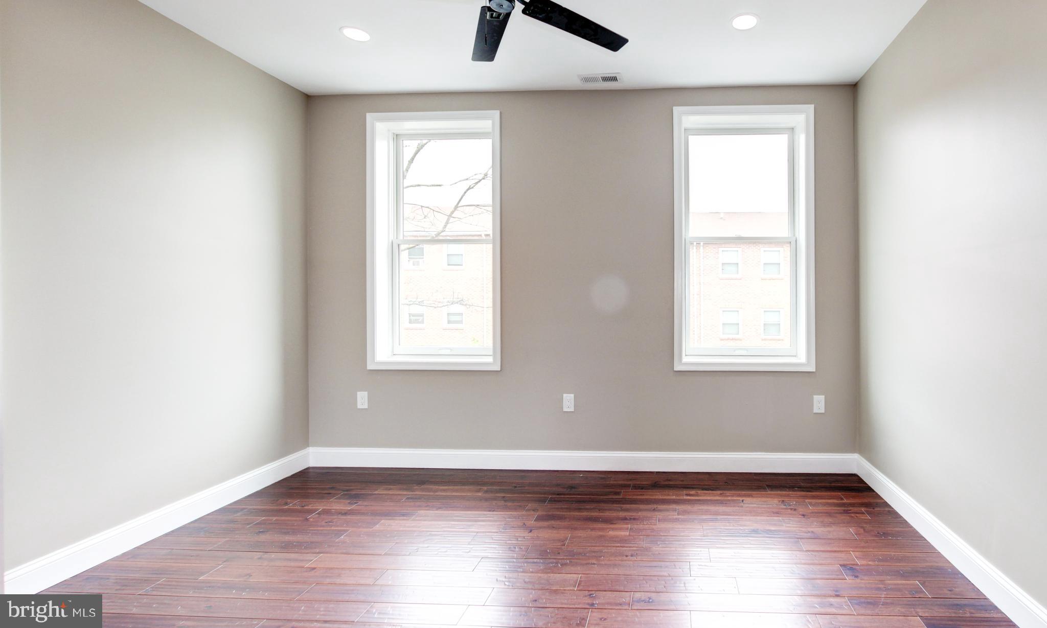 1324 Aisquith Street Baltimore, MD 21202 - Photo 13 of 47 an empty room with wooden floor windows and a ceiling fan