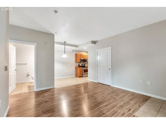 a view of an empty room with wooden floor and windows