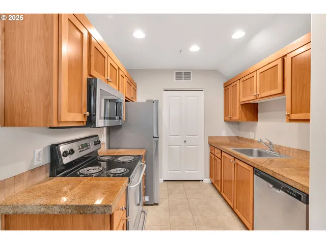 a kitchen with stainless steel appliances granite countertop a refrigerator a sink dishwasher and wooden cabinets