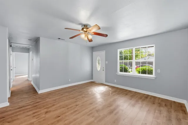 a view of an empty room with window and wooden floor