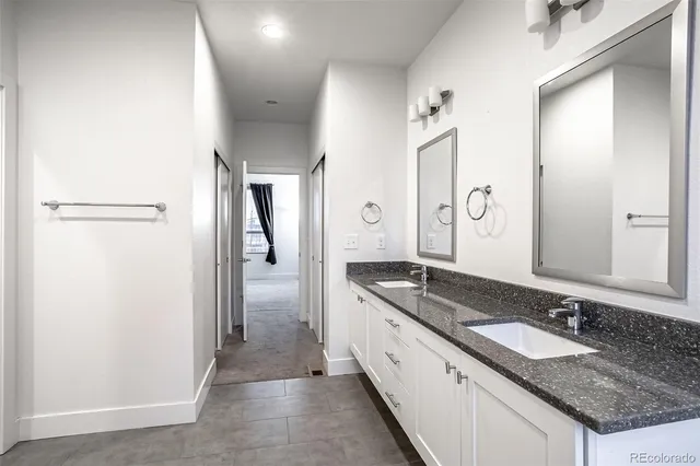 a bathroom with a granite countertop double vanity sink and a mirror