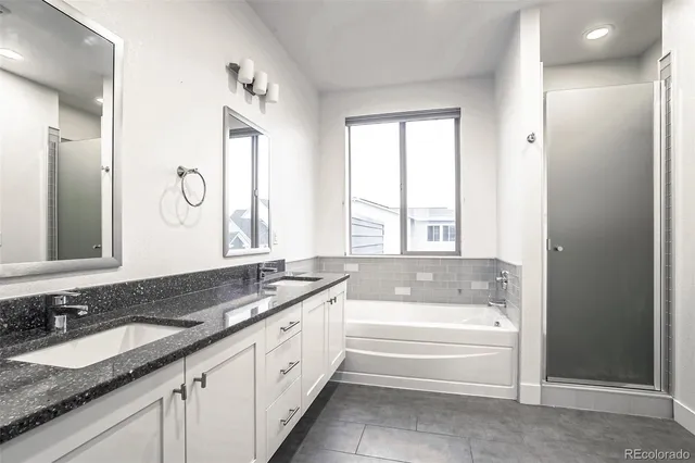 a bathroom with a granite countertop tub sink and mirror