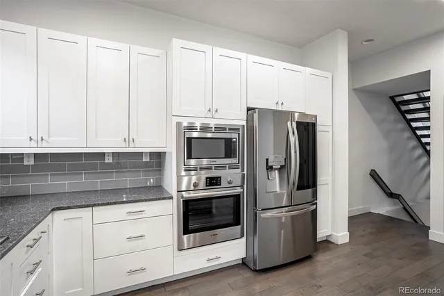 a kitchen with granite countertop white cabinets and stainless steel appliances