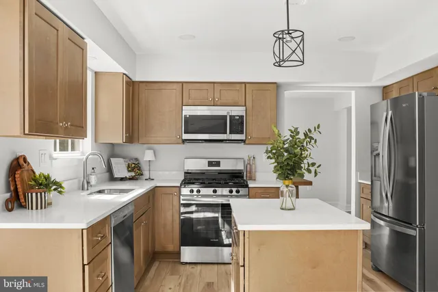 a kitchen with stainless steel appliances a stove a sink a microwave a refrigerator a stove and cabinets