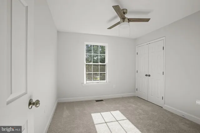 an empty room with a window and a fan