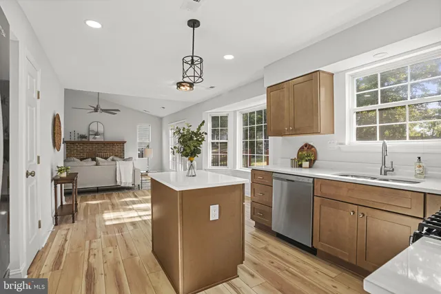a kitchen with kitchen island granite countertop a sink cabinets and wooden floor