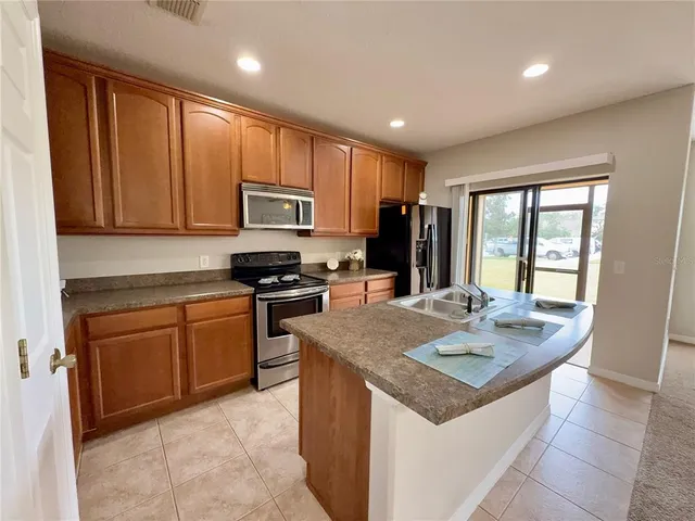 a kitchen with stainless steel appliances granite countertop a refrigerator stove top oven and sink