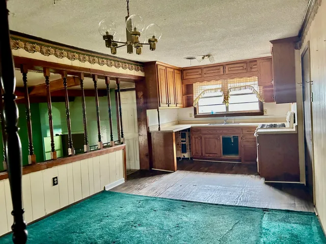 a large kitchen with stainless steel appliances granite countertop a stove and a view of living room