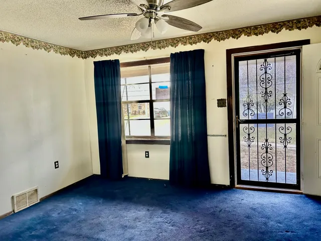 an empty room with windows and fan