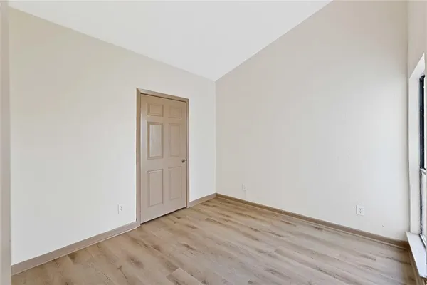 a view of an empty room with wooden floor and closet