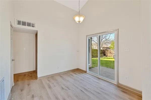 a view of an empty room with glass door and wooden floor