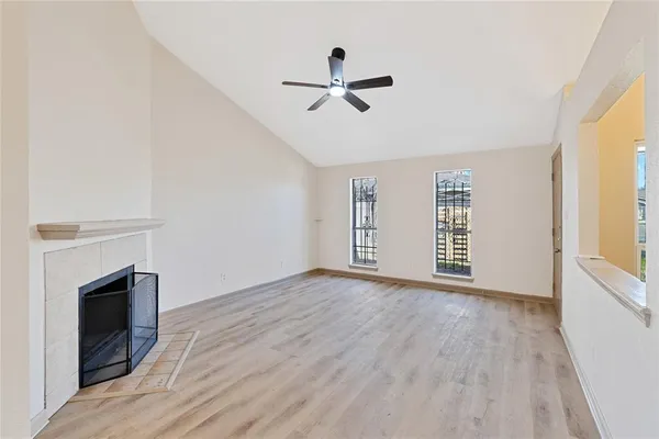 a view of empty room with wooden floor and fan