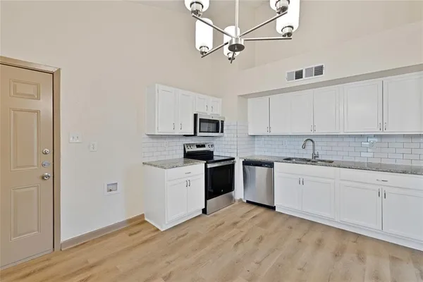 a kitchen with granite countertop a sink cabinets stainless steel appliances and a counter space