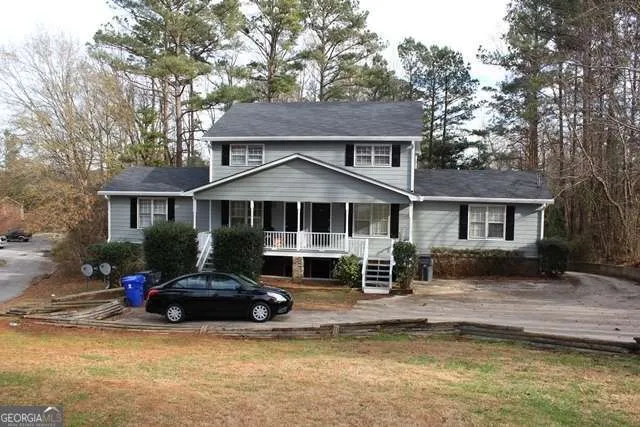 a front view of a house with a yard and a large tree