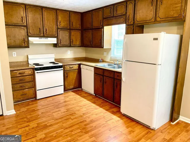 a kitchen with granite countertop a refrigerator and a stove top oven