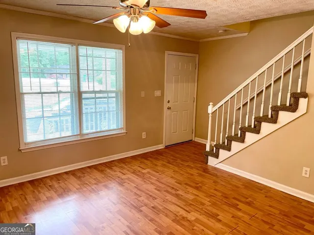 a view of an empty room with wooden floor and a window