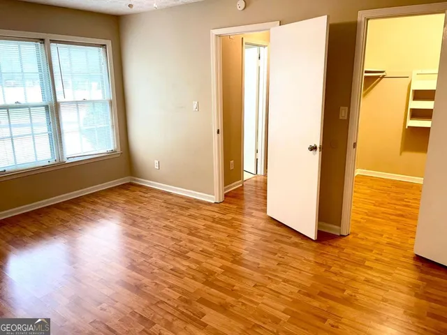 a view of an empty room with wooden floor and a window