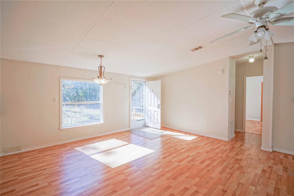 16621 Southwest 45th Street Ocala, FL 34481 - Photo 11 of 52 an empty room with wooden floor chandelier fan and windows