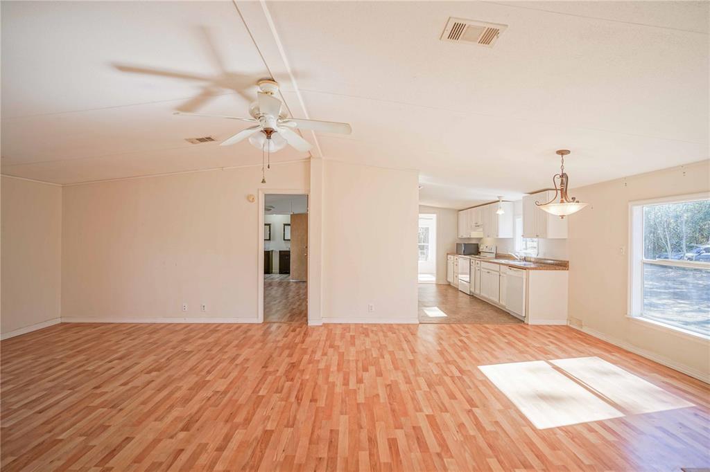 16621 Southwest 45th Street Ocala, FL 34481 - Photo 13 of 52 a empty room with wooden floor and kitchen view