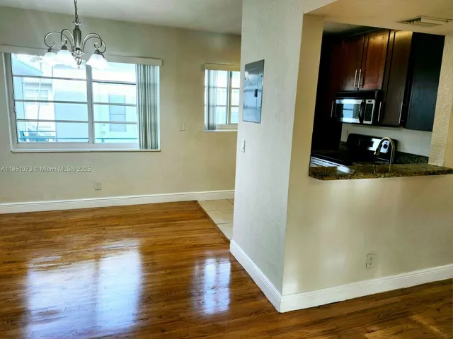 a view of empty room with window and wooden floor
