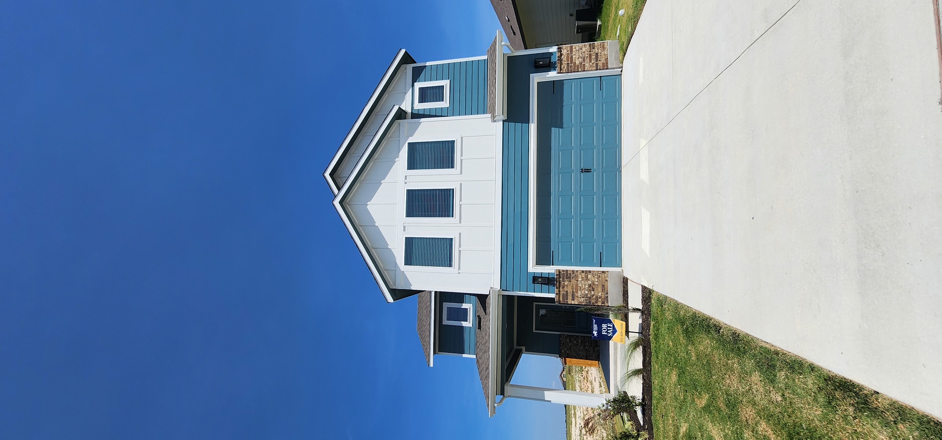 A striking contemporary residence boasts a welcoming covered entry and an attached garage with a paved driveway.