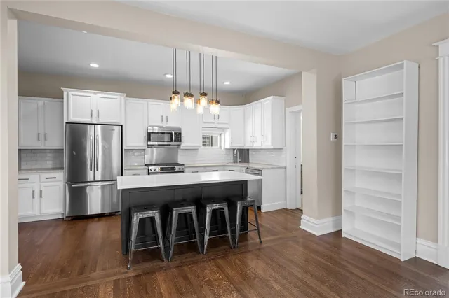 a kitchen with stainless steel appliances a table chairs refrigerator and cabinets
