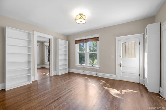 an empty room with wooden floor closet and windows