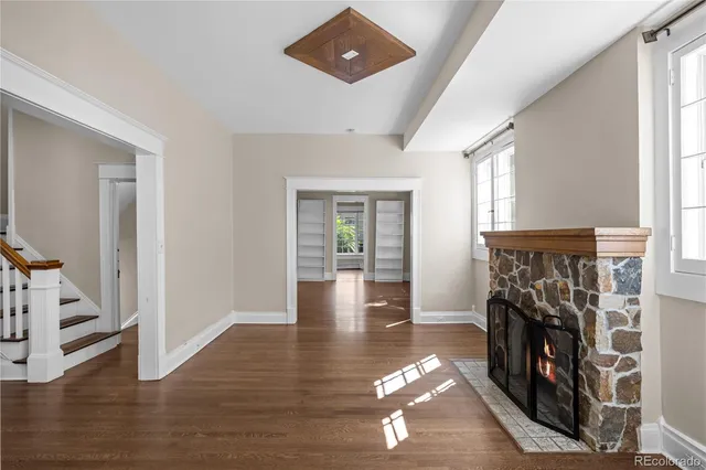 an empty room with windows a fireplace and wooden floor