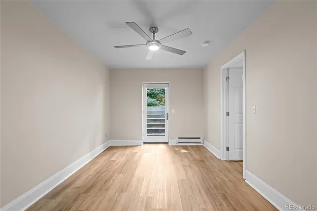 an empty room with wooden floor a ceiling fan and windows