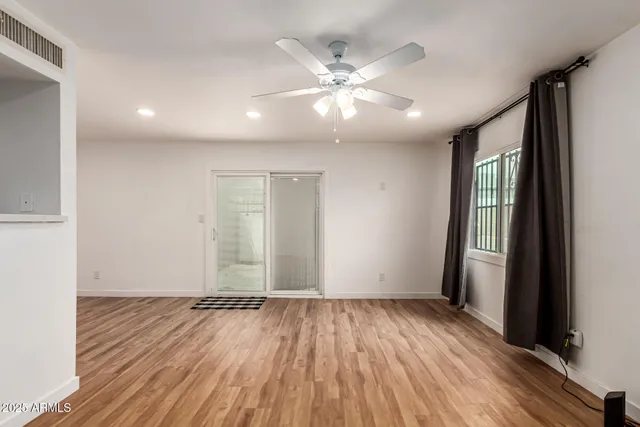 an empty room with wooden floor and windows