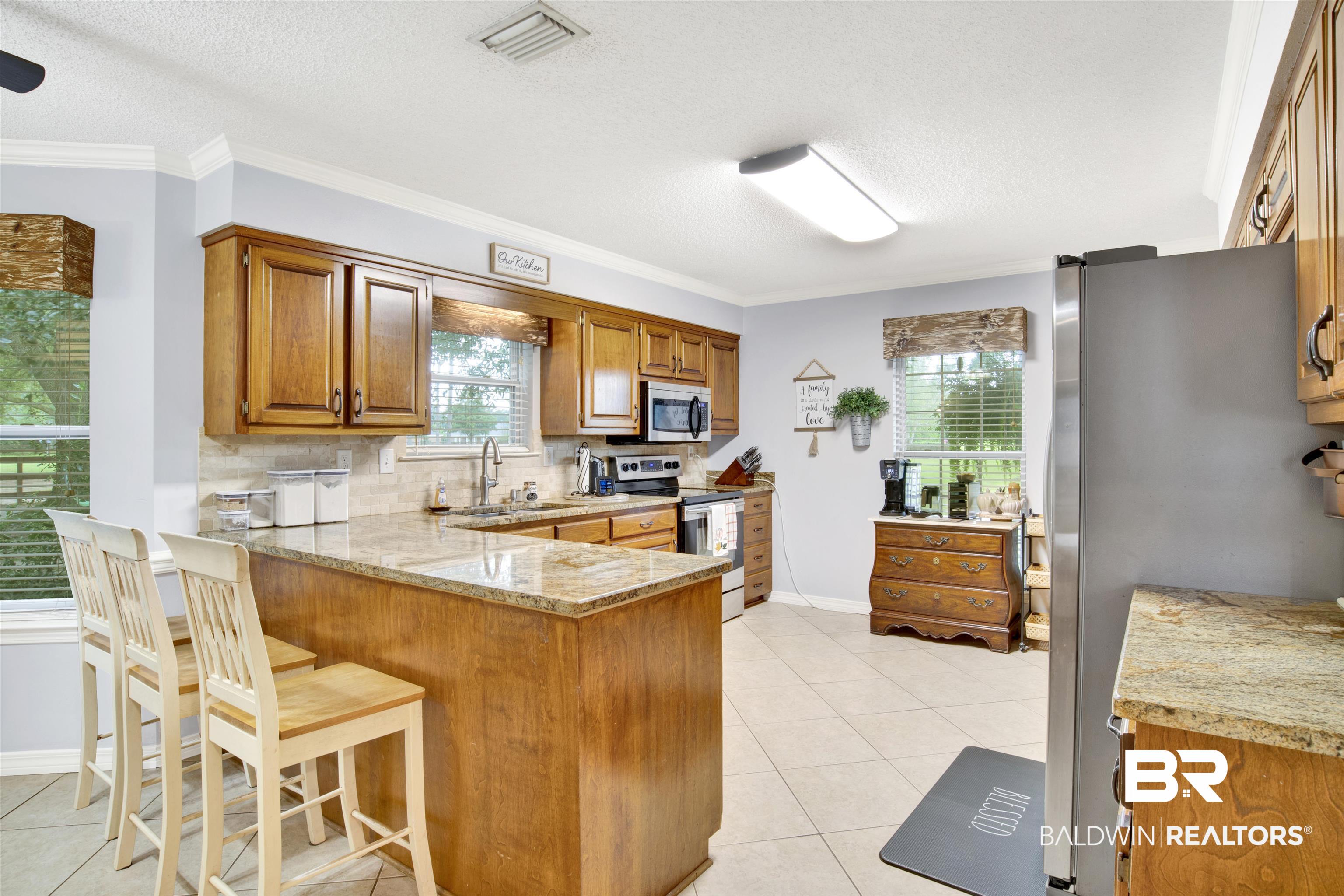 13385 Tom Gaston Road Mobile, AL 36695 - Photo 7 of 42 Kitchen with light stone counters, tasteful backsplash, stainless steel appliances, and a wealth of natural light