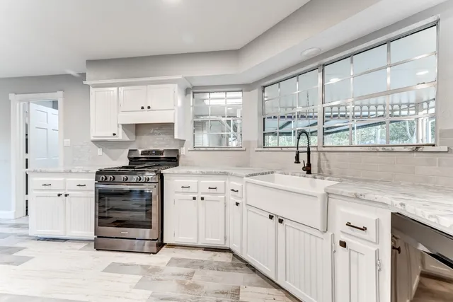 a kitchen with cabinets appliances a sink and a window