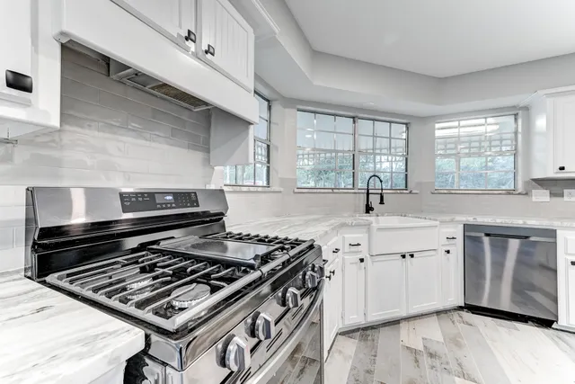 a kitchen with a stove a sink and wooden floor