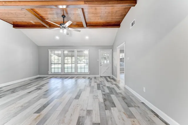 a view of an empty room with wooden floor and windows