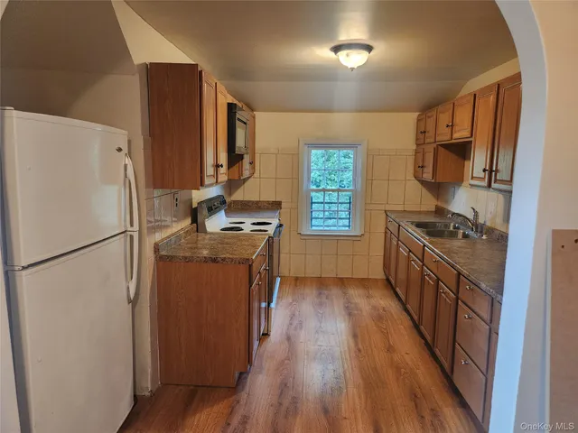 a kitchen with a refrigerator a stove top oven a sink and dishwasher with wooden floor